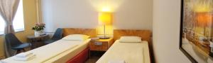 a room with two beds and a desk and a lamp at Hotel M68 in Berlin