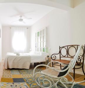 1 dormitorio con cama y mecedora en Urban Suites El Postigo, en Córdoba