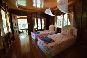 two beds in a room with windows at Namtok Bungalows in Ko Yao Noi