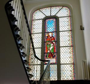 a large stained glass window in a stair case at Sint Jacobs in Bruges