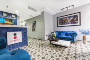 a living room with blue couches and a fireplace at Hotel London in Batumi