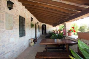 un patio al aire libre con mesa de madera y bancos en Terre Del Cantico Country House en Spello