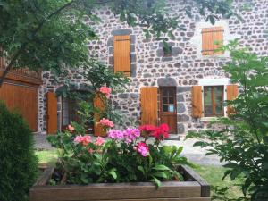 une maison en pierre avec des fleurs devant elle dans l'établissement Ferme de la Micezelle près le Puy en Velay, à Concis