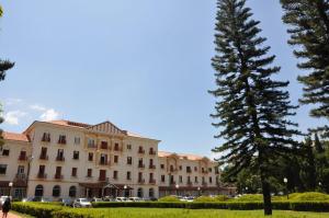 Un gran edificio con un árbol delante. en Hotel Salvador, en Poços de Caldas
