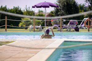 a child in a swimming pool with an umbrella at Residenza Principina in Principina Terra