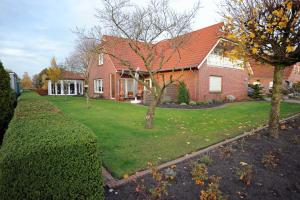 a red brick house with two trees in the yard at Ferienwohnung Schilling_ 65043 in Moormerland