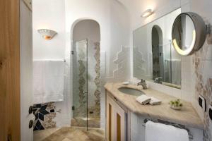 a bathroom with a sink, mirror, and bathtub at Grand Hotel Poltu Quatu in Porto Cervo