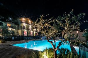 a swimming pool at night with a tree in the foreground at La Collina degli Ulivi in Vercana