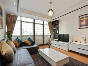 a living room with a couch and a tv at Serena Sathorn Suites in Bangkok
