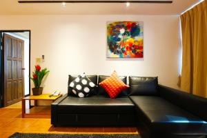 - un canapé en cuir noir dans un salon avec un tableau dans l'établissement Serena Sathorn Suites, à Bangkok