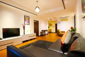 Il comprend un salon doté d'un canapé et d'une télévision à écran plat. dans l'établissement Serena Sathorn Suites, à Bangkok
