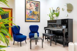 a living room with a piano and blue chairs at Piccadilly Rooms Restaurant and Beach in Santa Maria al Bagno