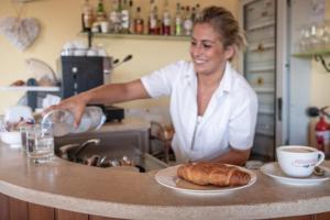 a woman standing in a kitchen with a plate of bread at Residenza Principina in Principina Terra