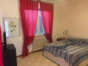 1 dormitorio con cortinas rojas, 1 cama y ventana en Appartamento Fano zona lido, en Fano