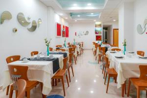 a dining room with white tables and wooden chairs at Piccadilly Rooms Restaurant and Beach in Santa Maria al Bagno