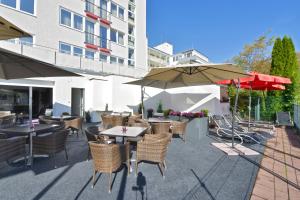 an outdoor patio with tables and chairs and umbrellas at ARTHOTEL Haar in Haar