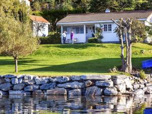 uma mulher em pé em frente a uma casa ao lado de um lago em 6 person holiday home in Volda em Ålesund