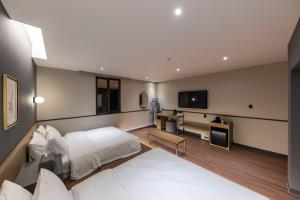 a hotel room with a bed and a flat screen tv at Brown Dot Hotel Seong Seo in Daegu