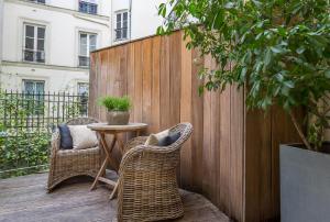 a patio with two chairs and a table and a fence at Hidden Hotel in Paris