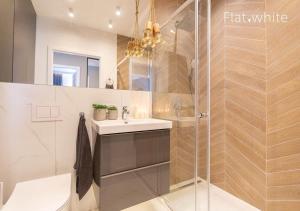 a bathroom with a sink and a glass shower at Apartamenty Flat White Obywatelska 47AB in Zielona Góra