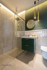 a bathroom with a shower and a sink and a toilet at Apartamenty Flat White Obywatelska 47AB in Zielona Góra