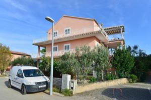 un coche blanco estacionado frente a una casa rosa en Apartments Martina, en Vodice