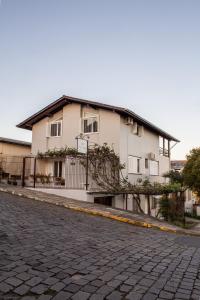 uma casa branca com uma cerca ao lado de uma rua em Pousada Don Marini em Bento Gonçalves