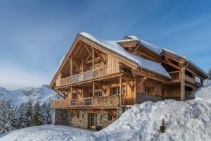 una cabaña de madera en la nieve con nieve en Chalet Lodge Oberig Exclusive en Villard-Reculas