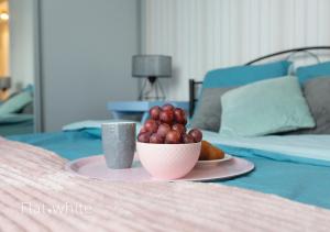 a plate with a bowl of fruit on a bed at Apartamenty Flat White Zamkowa 4-6 in Zielona Góra