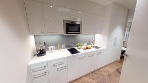 a white kitchen with a sink and a microwave at VISIONAPARTMENTS Bellariastrasse - self check-in in Zurich