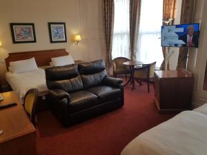 una camera d'albergo con divano e sedia di Welbeck Hotel & Apartments a Douglas