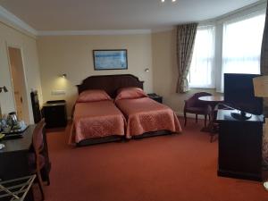 a bedroom with a bed and a desk and a television at Welbeck Hotel & Apartments in Douglas