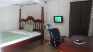 1 dormitorio con cama, mesa y TV en Dubai Resort Hotel, en Adjumani