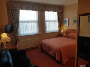 a hotel room with a bed and two windows at Welbeck Hotel & Apartments in Douglas