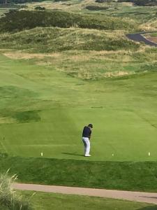 a man standing on a golf green with a ball at 3, The Links in Portrush