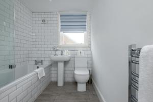 a bathroom with a toilet and a sink and a window at Marine Park - Perfect Elie Base - 1 min to Beach in Elie