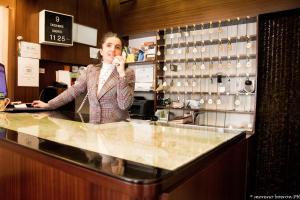 Un uomo in piedi dietro un bancone che parla al cellulare di Albergo Residence Italia Vintage Hotel a Pordenone