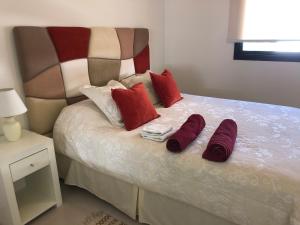 a bed with two red pillows and two towels on it at Departamento boutique en nueva cordoba in Córdoba