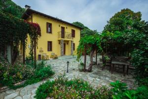 a yellow house with a patio in a garden at Ellis Full Guest House in Tsagarada