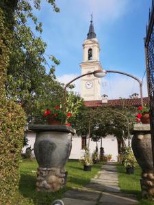 un edificio blanco con una torre del reloj y un edificio con flores en Ostello del Monastero, en Dronero