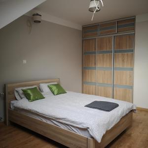 a bedroom with a large bed with green pillows at Konarskiego Apartments in Słupsk