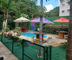 uma piscina com um guarda-sol, uma mesa e cadeiras em Pousada Casa de Vó em Eusébio
