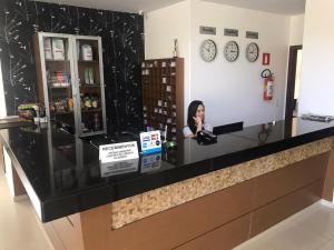 a woman sitting at a counter in a store at Guines Palace Hotel in Patrocínio
