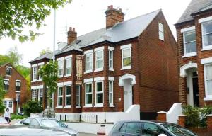 a red brick house with cars parked in front of it at Riverside Hotel in Norwich