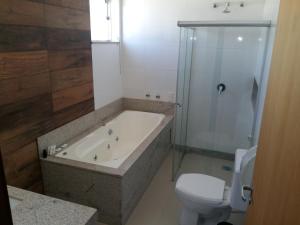 a bathroom with a tub and a toilet and a shower at Guines Palace Hotel in Patrocínio