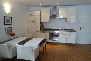 a kitchen with a dining room table and white cabinets at Ferienwohnung Meding am See in Schondorf am Ammersee