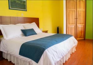 a bedroom with a large bed with a blue pillow on it at Ecohotel La Casona Pereira in Pereira