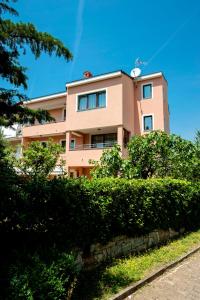 un edificio rosa con arbustos delante de él en Apartments Centener, en Rovinj