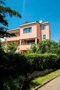 różowy budynek z krzakami przed nim w obiekcie Apartments Centener w Rovinj
