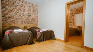 a room with two beds and a brick wall at Kaķītis in Sigulda